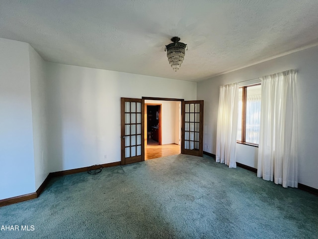 spare room with carpet flooring, french doors, a textured ceiling, and a notable chandelier