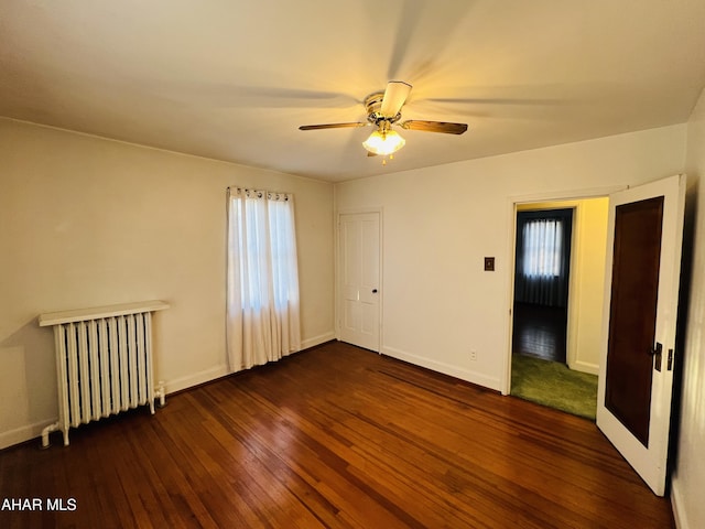 spare room featuring radiator, ceiling fan, and dark hardwood / wood-style flooring