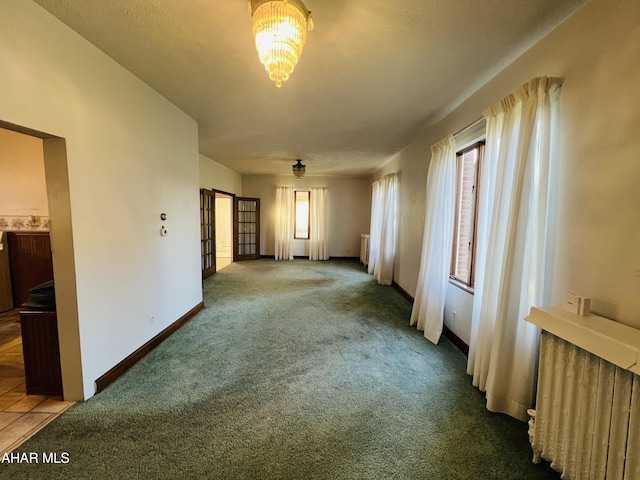 carpeted empty room with a notable chandelier