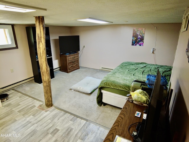 bedroom featuring a textured ceiling, light hardwood / wood-style flooring, and baseboard heating