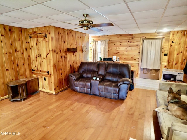 living room featuring a paneled ceiling, wooden walls, and wood-type flooring