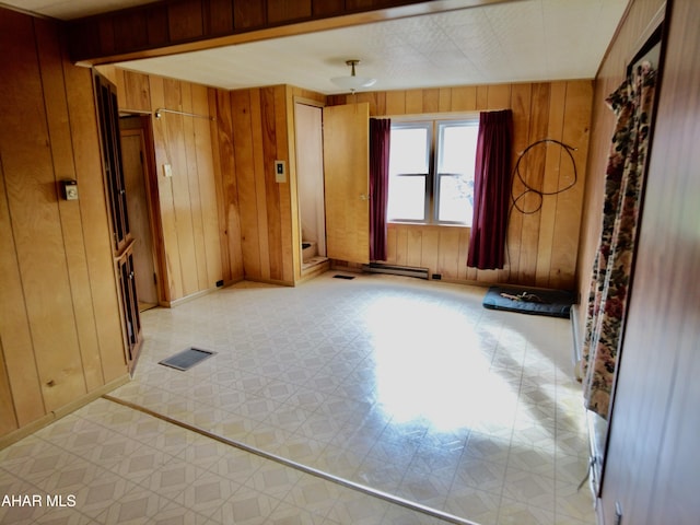 unfurnished room with wood walls and a baseboard heating unit