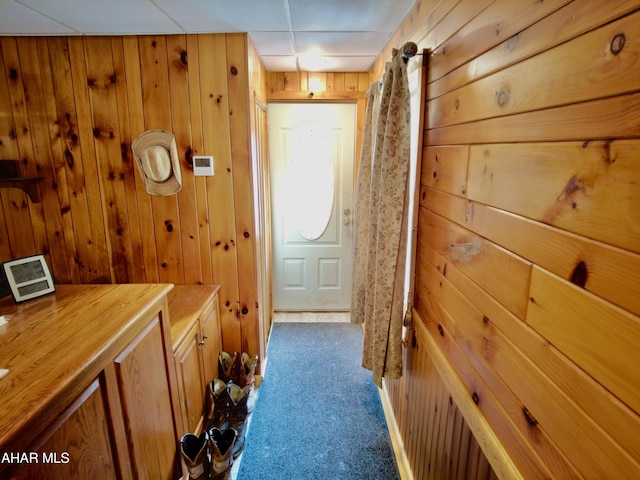 hallway featuring wood walls and dark carpet