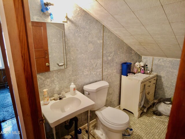 bathroom featuring toilet, tile patterned floors, vaulted ceiling, and sink