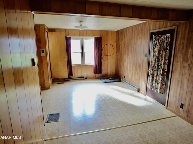 spare room featuring baseboard heating and wood walls