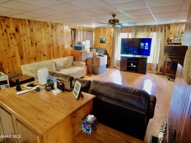 living room with a paneled ceiling, wooden walls, ceiling fan, and light hardwood / wood-style floors