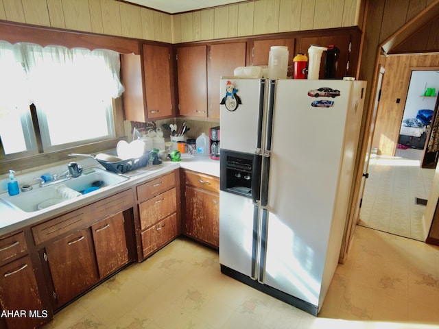 kitchen featuring wood walls, sink, and fridge with ice dispenser