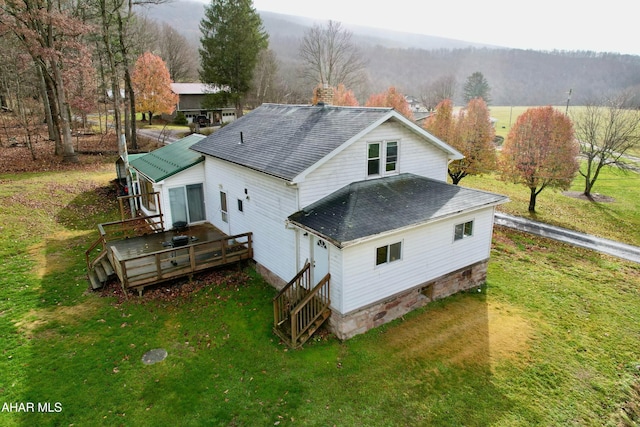 back of property with a wooden deck and a yard