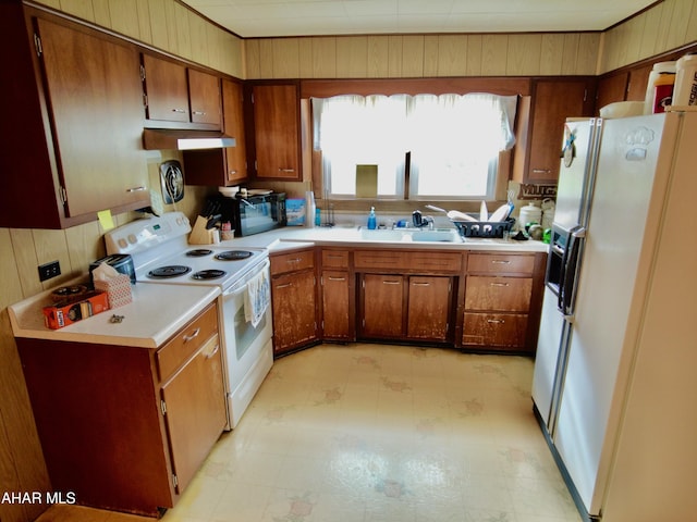 kitchen featuring fridge with ice dispenser, wood walls, sink, and white range with electric cooktop