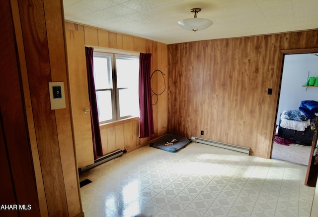 unfurnished room with baseboard heating and wood walls