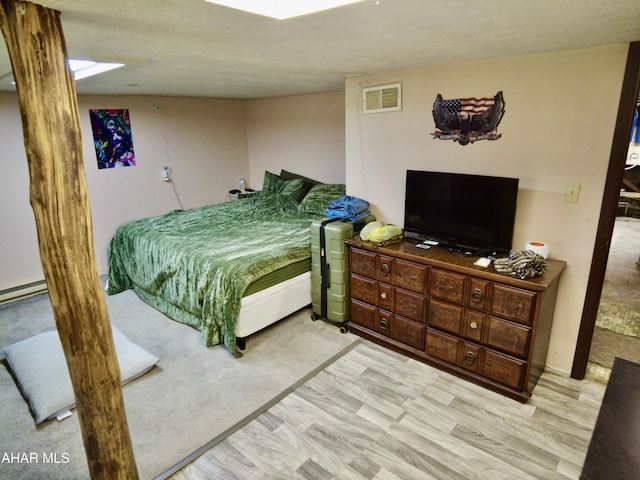 bedroom with light hardwood / wood-style floors and a textured ceiling