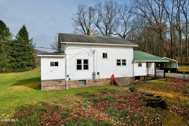 rear view of property featuring a lawn and a carport