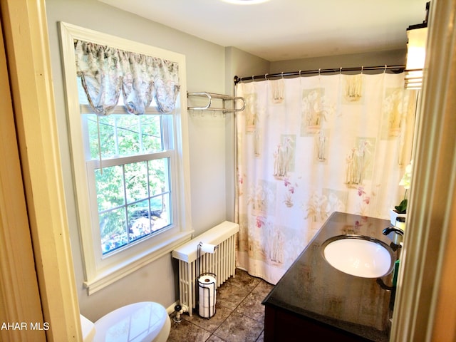 bathroom with tile patterned flooring, vanity, radiator heating unit, and a wealth of natural light