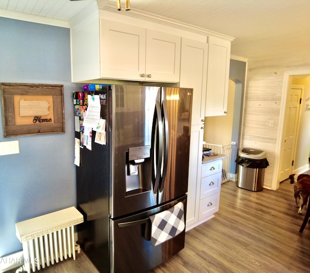 kitchen with hardwood / wood-style floors, wood walls, white cabinets, crown molding, and stainless steel refrigerator with ice dispenser