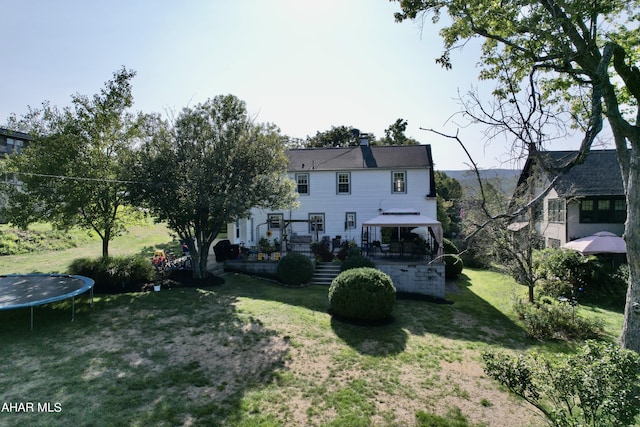 back of house with a gazebo, a lawn, a patio, and a trampoline