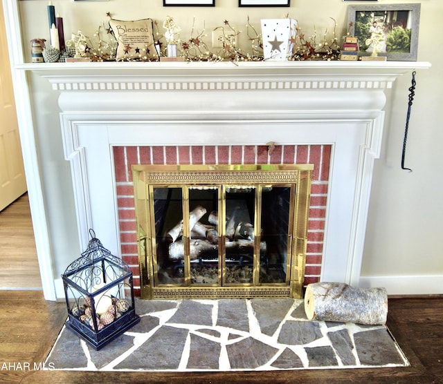 interior details with wood-type flooring and a brick fireplace