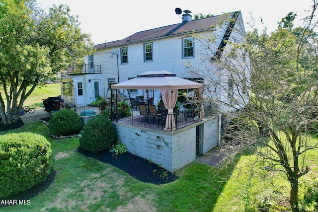 rear view of house featuring a gazebo, a balcony, and a lawn