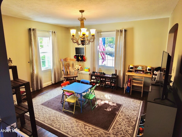 playroom featuring a notable chandelier, dark hardwood / wood-style floors, plenty of natural light, and a textured ceiling