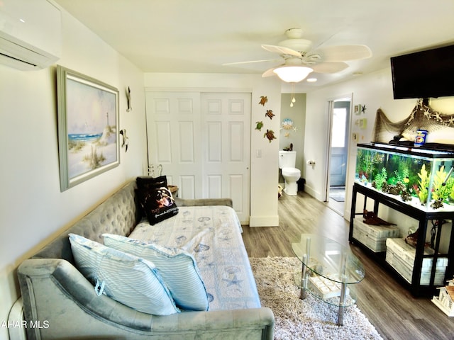 sitting room featuring a wall mounted air conditioner, ceiling fan, and hardwood / wood-style flooring