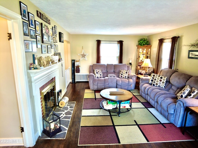 living room with a fireplace, a textured ceiling, radiator, and dark wood-type flooring