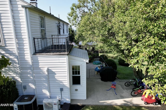 view of home's exterior with a balcony, a patio, central AC unit, and ac unit