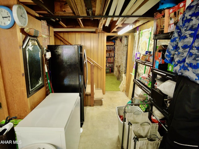 basement with wood walls and black fridge