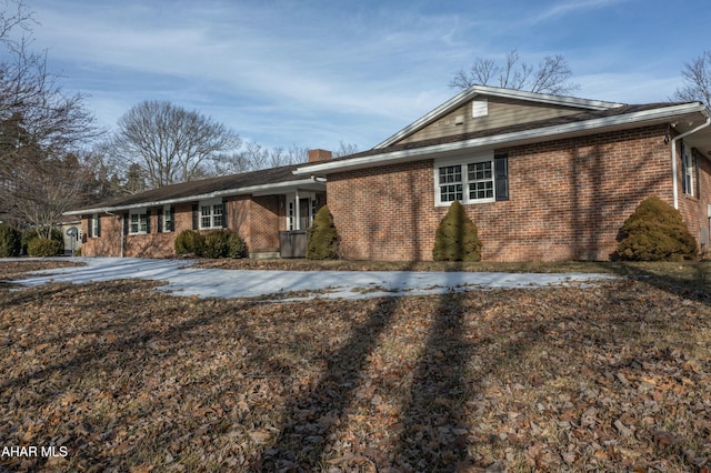 ranch-style house featuring brick siding and a chimney