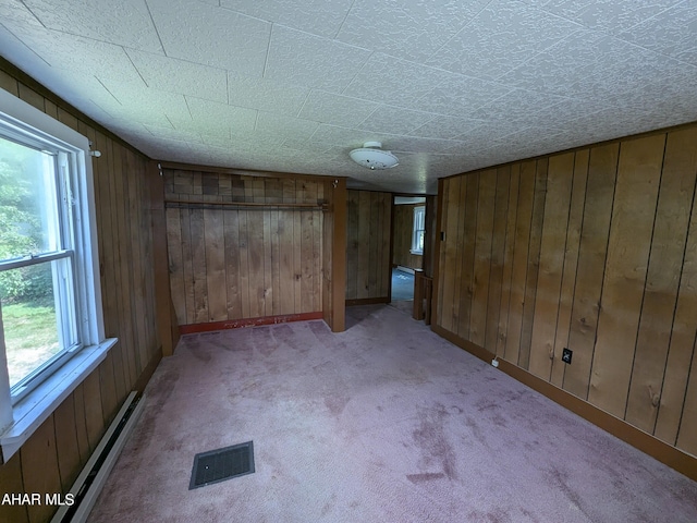 spare room featuring wood walls, light colored carpet, and baseboard heating