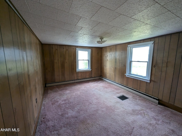 unfurnished room featuring light colored carpet, baseboard heating, and wooden walls