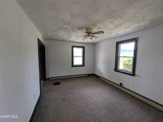 empty room featuring baseboard heating, carpet floors, and a healthy amount of sunlight