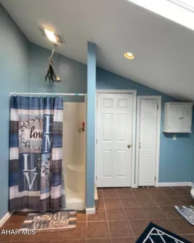 bathroom with vaulted ceiling, a shower with curtain, tile patterned floors, and baseboards