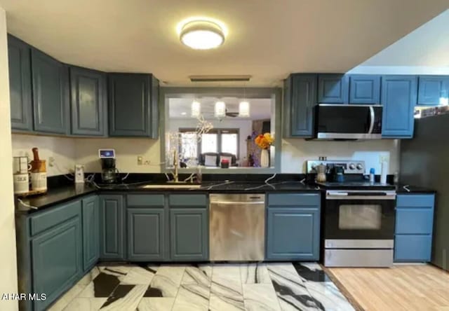 kitchen featuring stainless steel appliances, a sink, dark countertops, and a chandelier