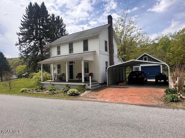 193 Pavia Rd, Imler, PA 16655 - farmhouse featuring a porch, a chimney, a detached carport, and decorative driveway