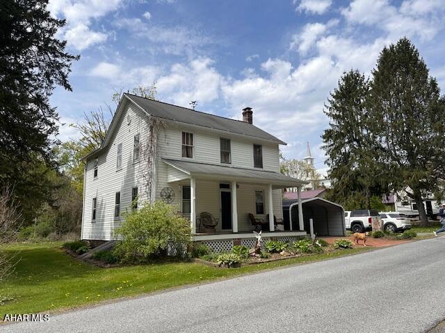 193 Pavia Rd, Imler, PA 16655 - farmhouse-style home with a chimney, a detached carport, covered porch, and a front lawn