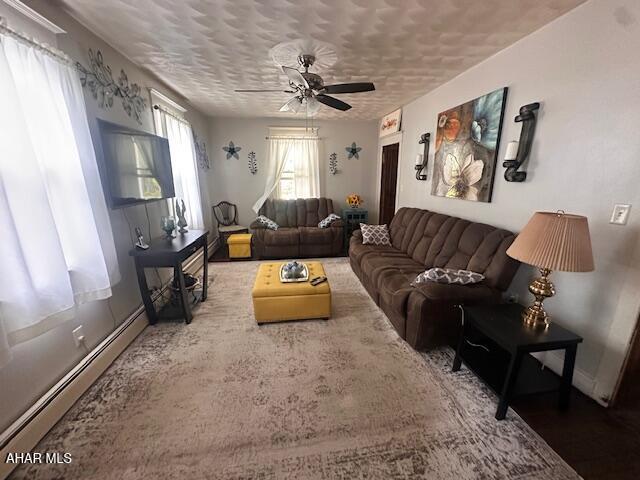 193 Pavia Rd, Imler, PA 16655 - living area with baseboard heating, a ceiling fan, a textured ceiling, and baseboards