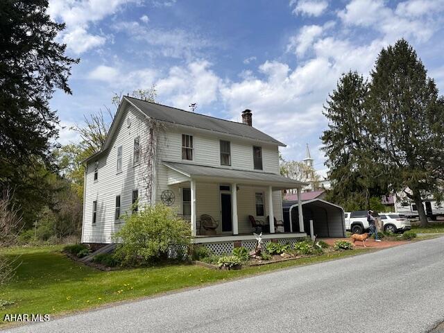 193 Pavia Rd, Imler, PA 16655 - country-style home featuring a chimney, covered porch, a detached carport, and a front lawn