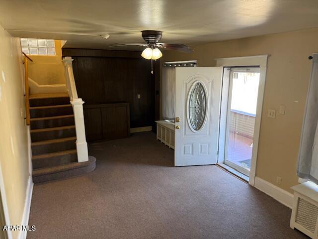 carpeted foyer featuring stairway, ceiling fan, and baseboards