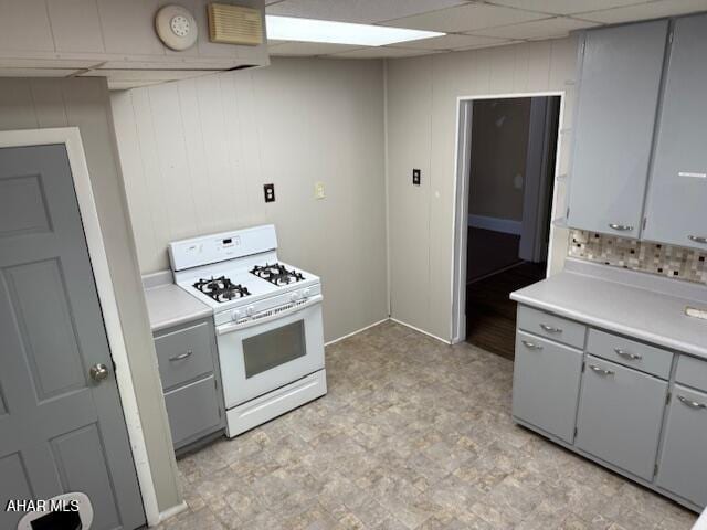 kitchen with gray cabinetry, light floors, light countertops, white range with gas cooktop, and a paneled ceiling