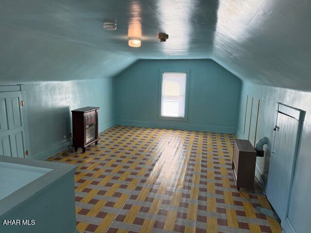 additional living space featuring baseboards and lofted ceiling