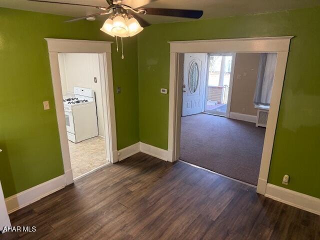 unfurnished room featuring baseboards, dark wood-style flooring, and ceiling fan