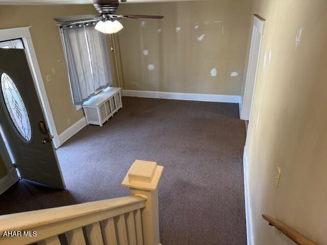 carpeted entrance foyer featuring baseboards and ceiling fan