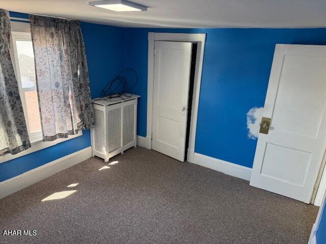 unfurnished bedroom featuring carpet flooring, radiator heating unit, and baseboards