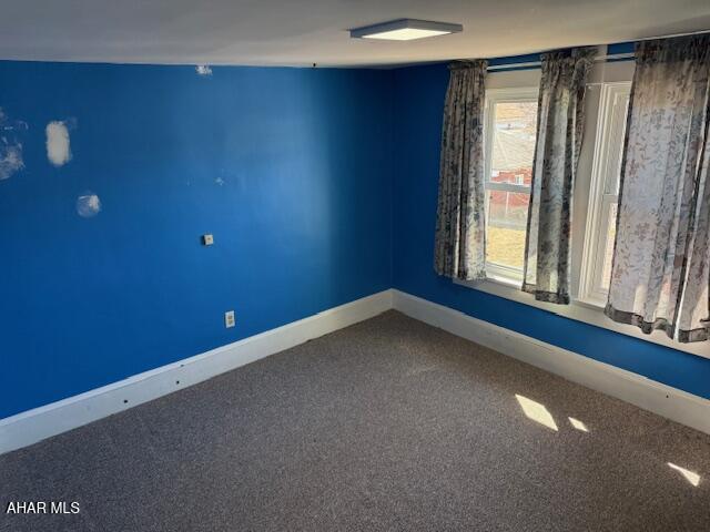 carpeted spare room featuring baseboards