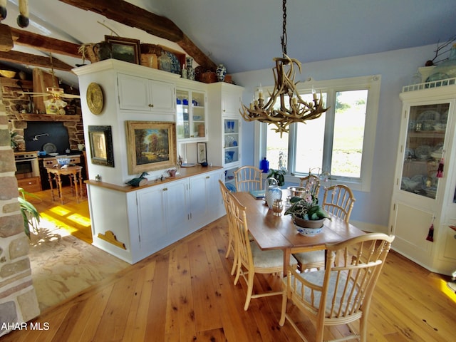 dining room featuring vaulted ceiling with beams, an inviting chandelier, and light hardwood / wood-style flooring