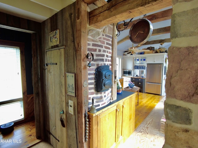 kitchen featuring appliances with stainless steel finishes, white cabinetry, light hardwood / wood-style flooring, and beam ceiling