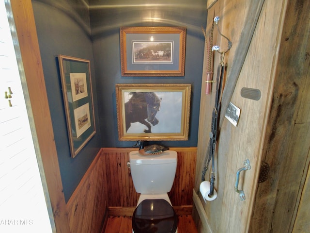 bathroom with wood walls and toilet