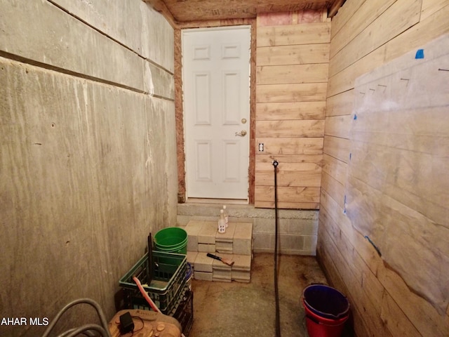 miscellaneous room featuring concrete floors and wood walls