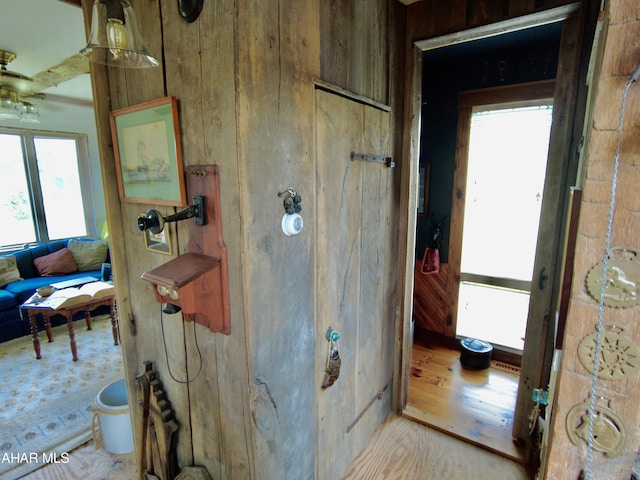 bathroom with hardwood / wood-style floors, ceiling fan, and wooden walls