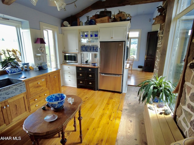 kitchen with a wealth of natural light, stainless steel appliances, lofted ceiling, and light wood-type flooring