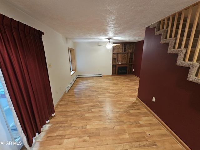 interior space featuring ceiling fan, light hardwood / wood-style flooring, a baseboard radiator, and a textured ceiling